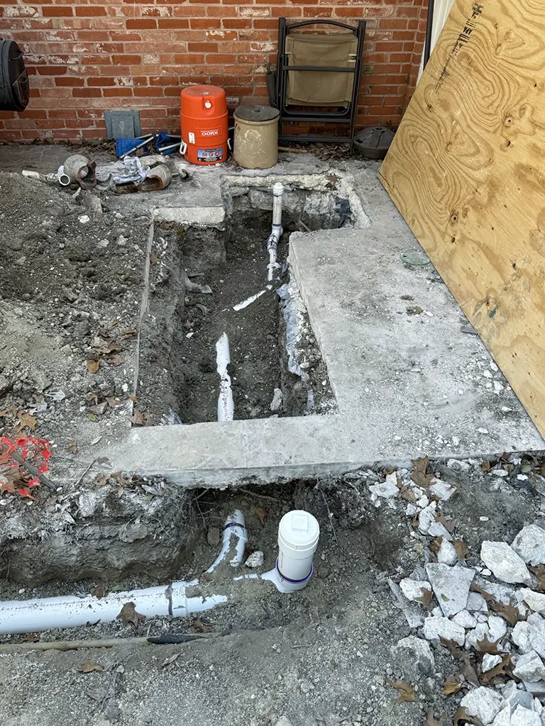 Patriot Plumbing technicians replacing a sewer line with new PVC pipe in a San Antonio TX home foundation