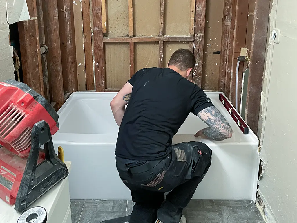Patriot Plumbing technician installing a new bathtub during a bathroom remodel in a San Antonio TX home