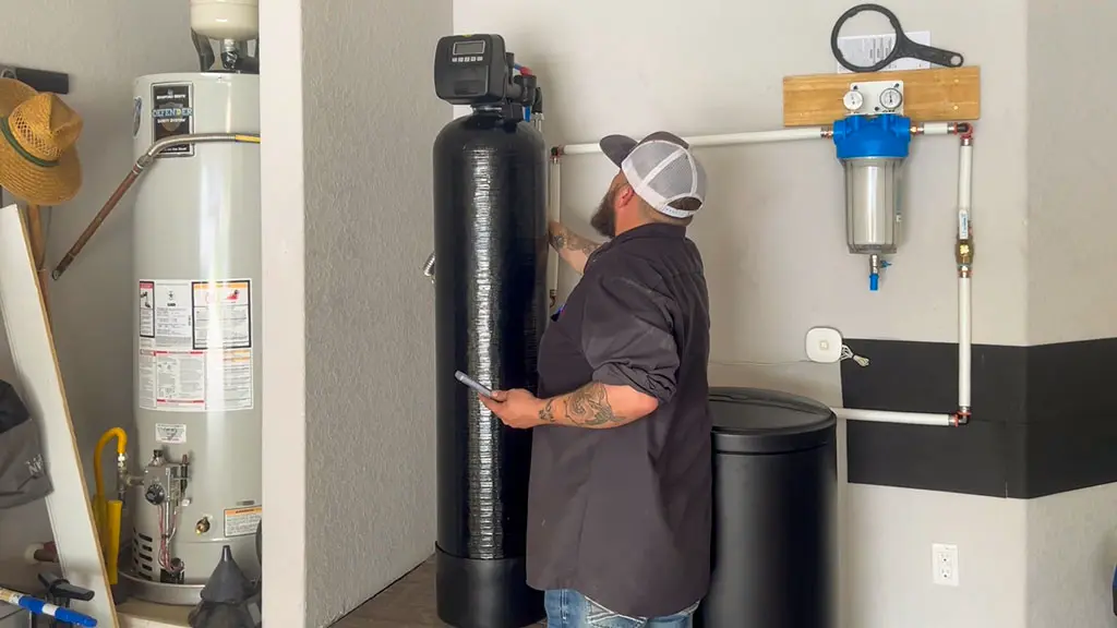 Patriot Plumbing technician installing a whole-home water softener and filtration system in a San Antonio TX home