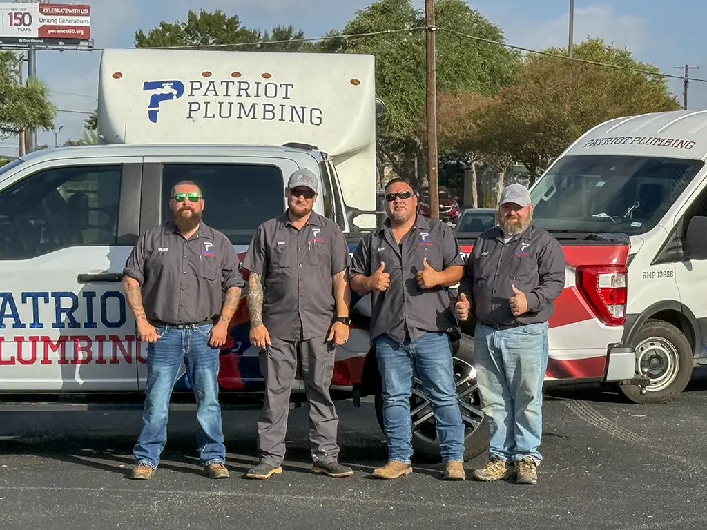 Team of four licensed Patriot Plumbing emergency plumbers in San Antonio, TX standing in front of branded service trucks and vans