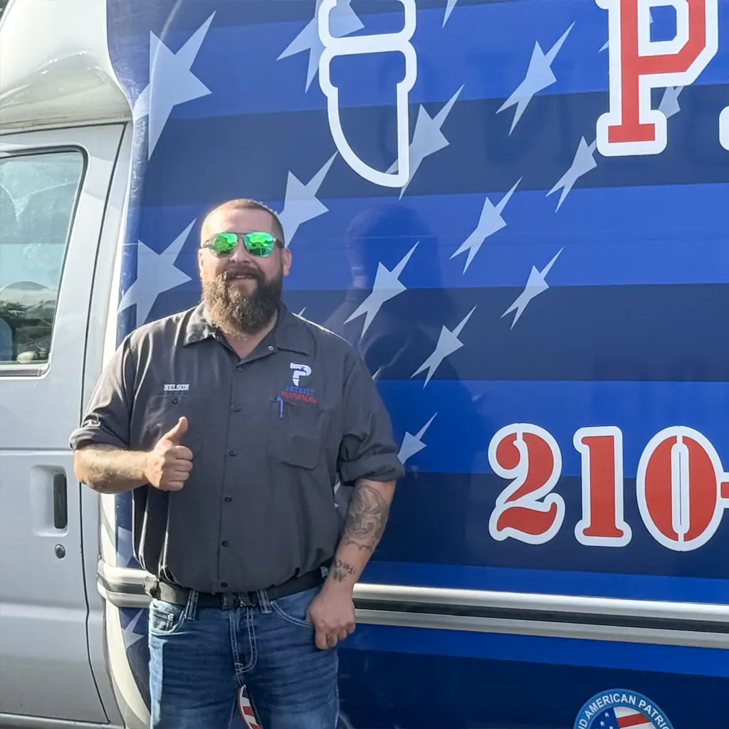 Patriot Plumbing plumber in San Antonio, Texas giving a thumbs up beside an American flag wrapped service van