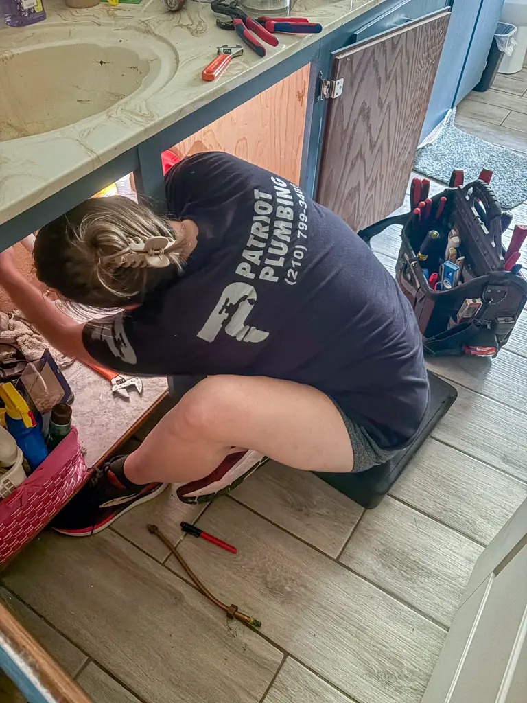 Licensed San Antonio plumber performing under-sink repair work with professional tools