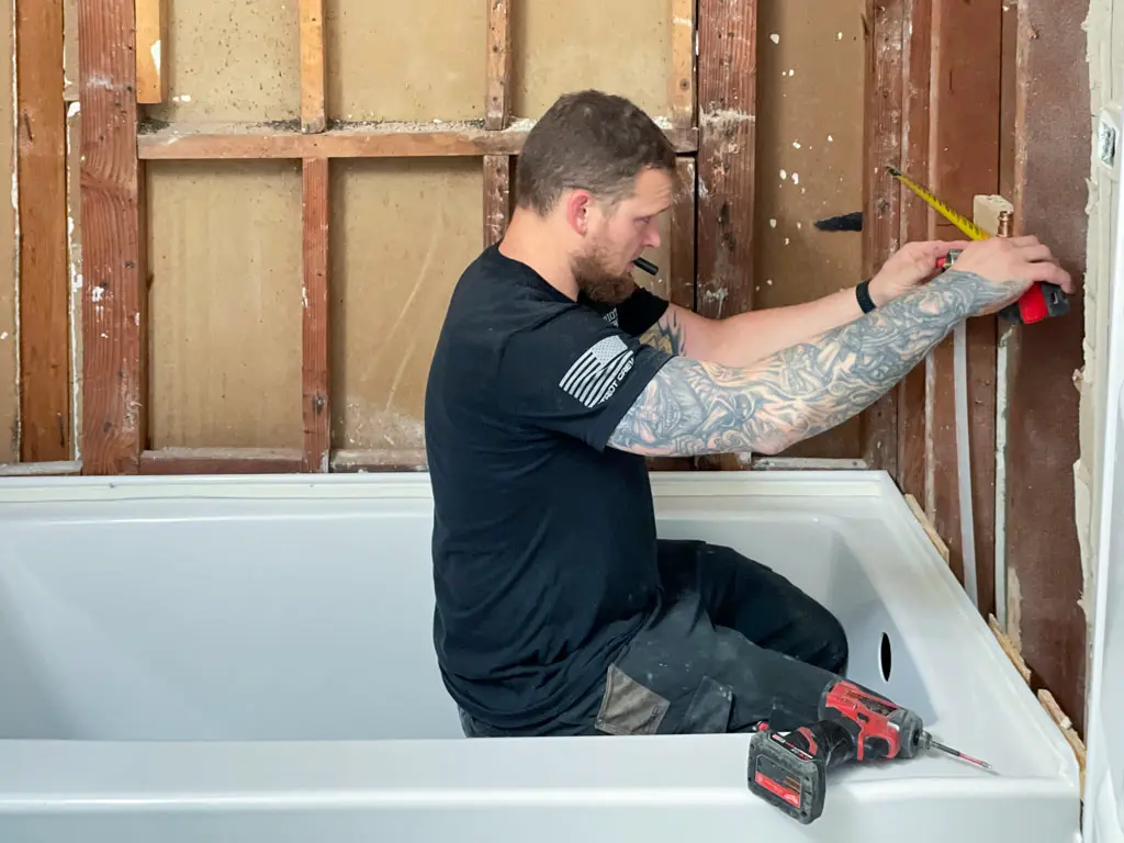 Patriot Plumbing technician measuring for bathtub installation in San Antonio home