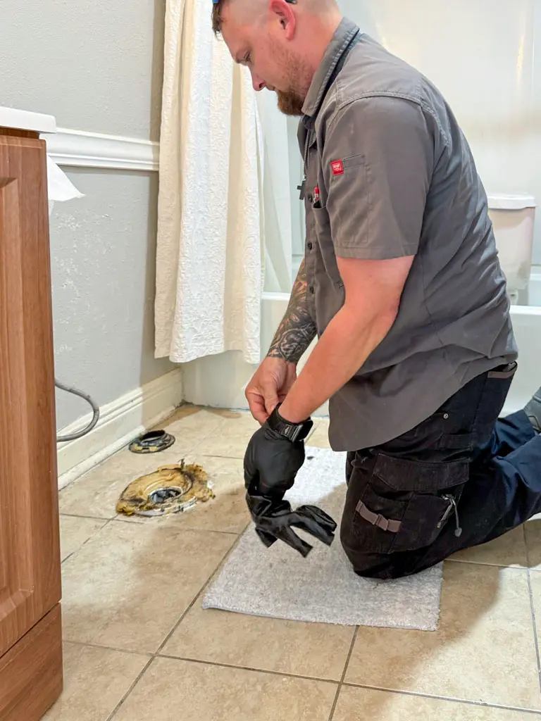 Professional plumber preparing toilet flange repair in San Antonio bathroom
