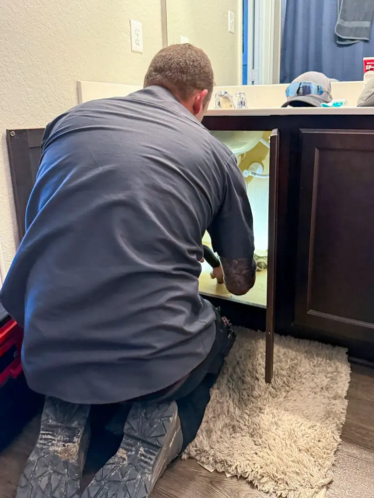 Experienced plumber servicing bathroom vanity plumbing in San Antonio residence
