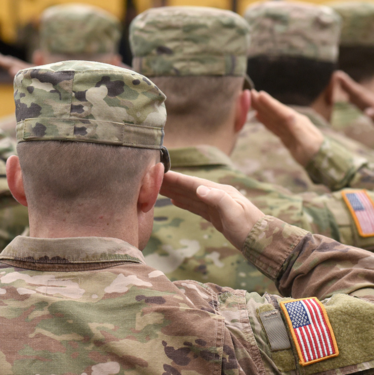 Military service members saluting with American flag patches